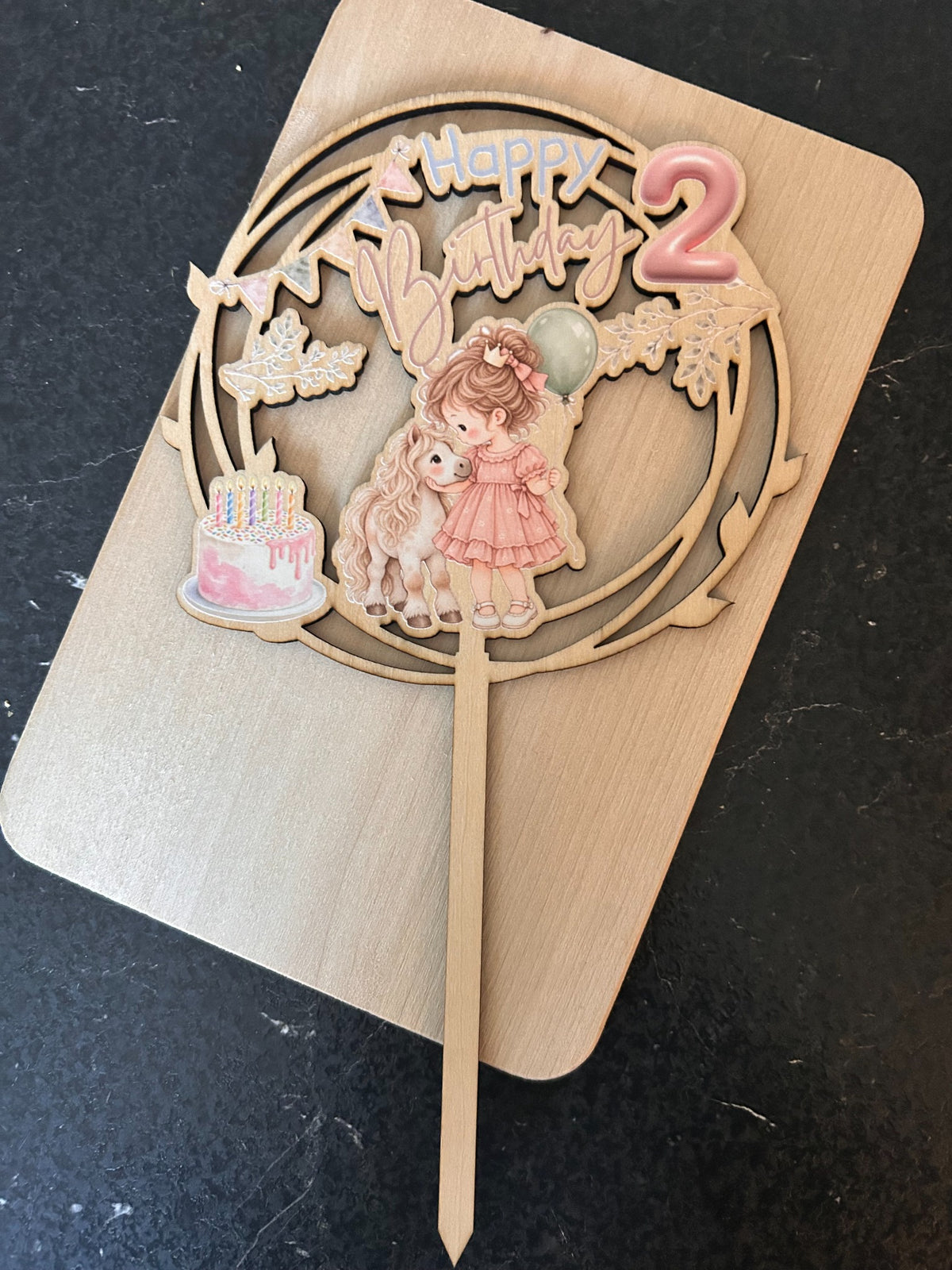 Caketopper aus Holz zum zweiten Geburtstag mit Mädchen, Pony, Torte und farbigem Happy-Birthday-Schriftzug.