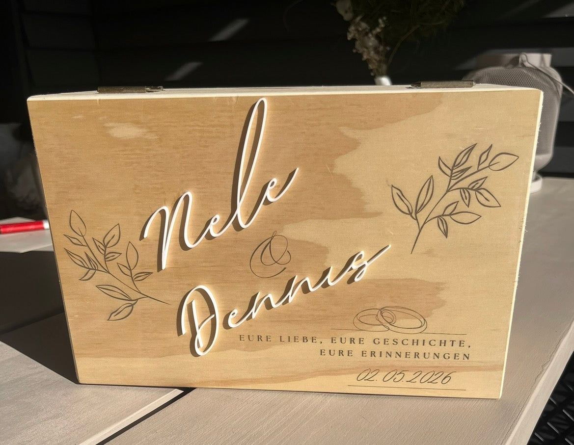 Deckel einer Hochzeitsbox aus Holz mit zwei weißen aufgesetzten Namen und gravierten Zweigen.