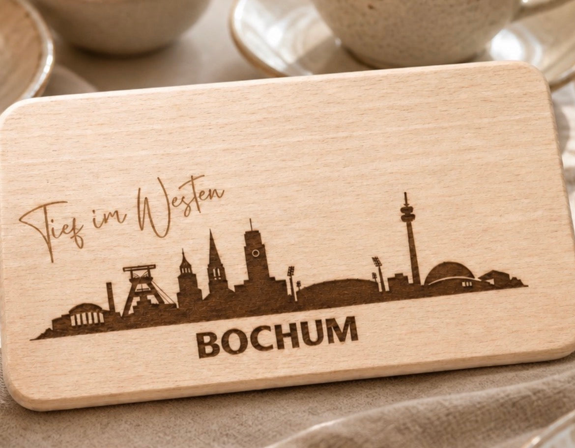 Holzbrett mit gravierter Bochumer Skyline und den Schriftzügen Tief im Westen und Bochum.