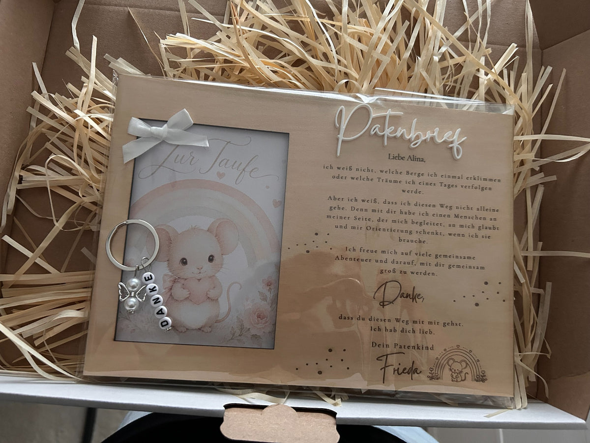 Patenbrief aus Holz mit Mäuschen und Regenbogen, weißer Schleife und Schlüsselanhänger in einer Geschenkbox.