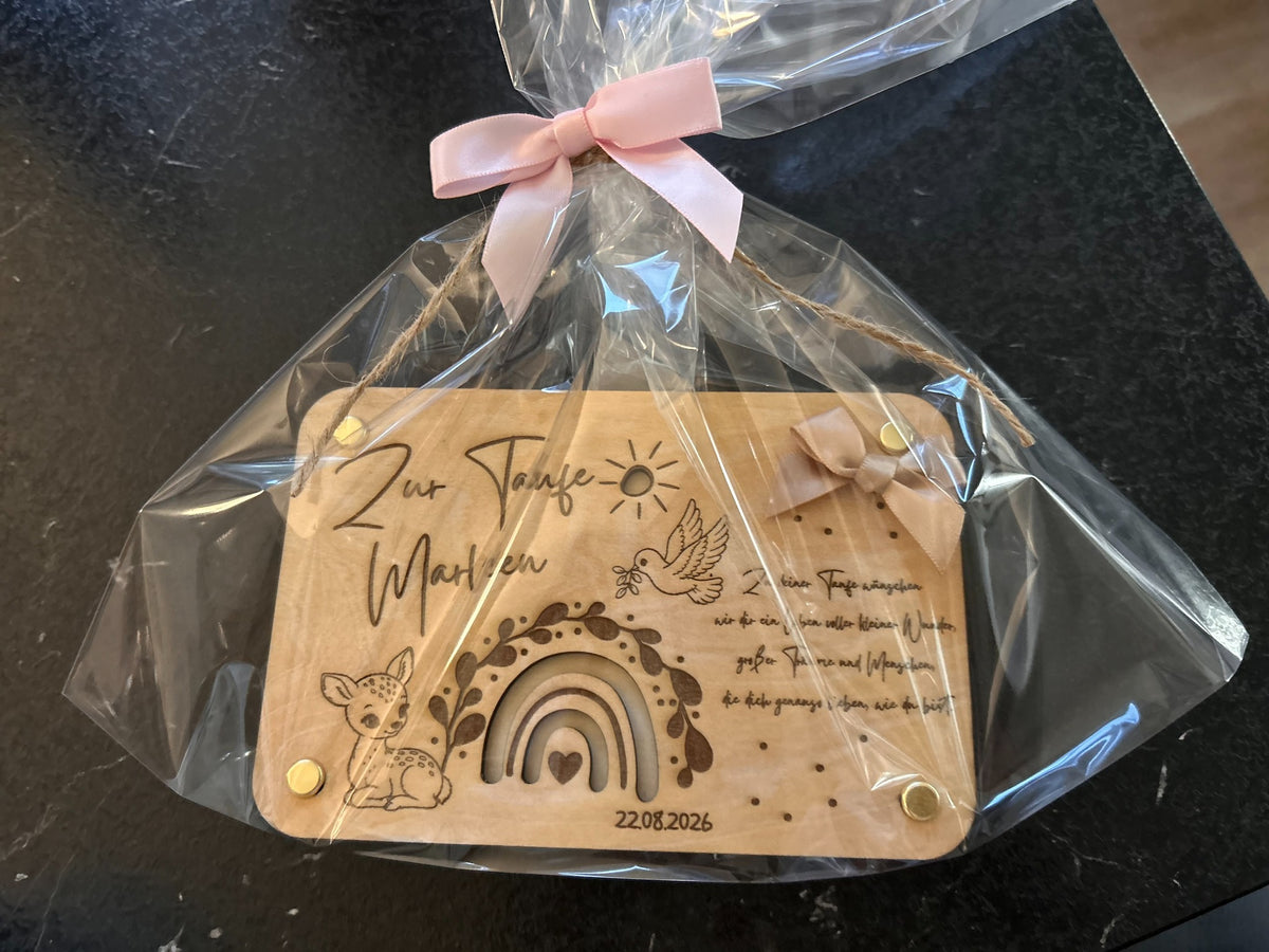 Verpacktes Taufgeschenk aus Holz mit Namen, Datum, Regenbogen, Rehmotiv und rosa Schleife.